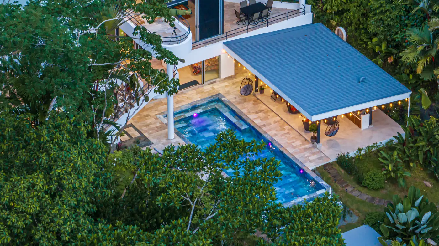 Vista cenital de la piscina infinita de agua salada y la terraza techada rodeadas de árboles