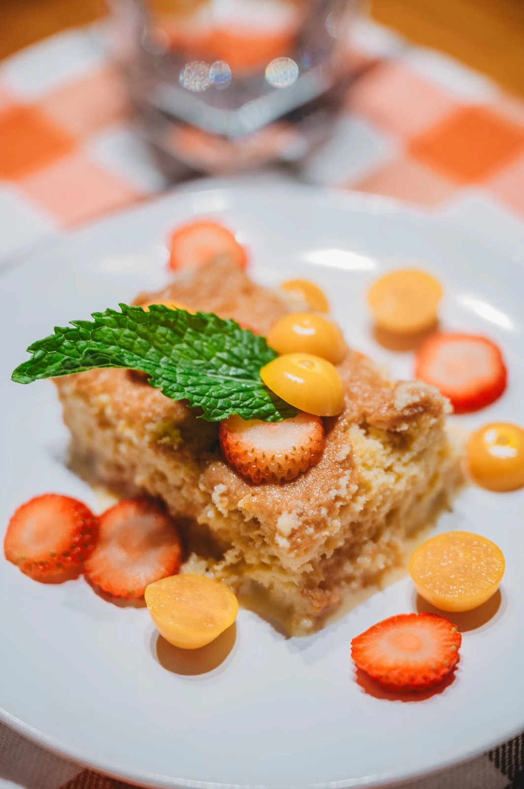 Slice of tres leches cake with strawberries, golden berries, and mint