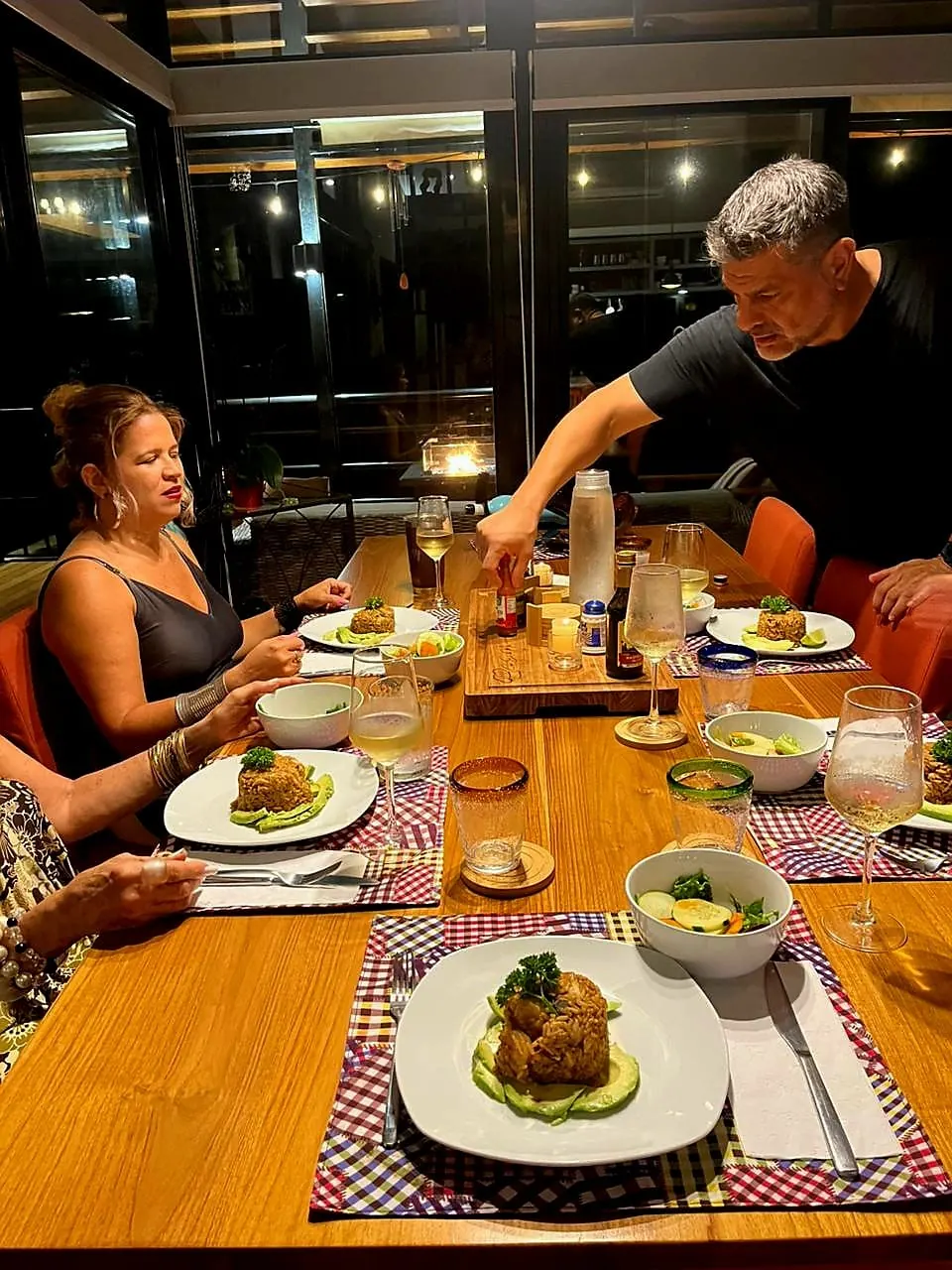 Chef Eddie serving plated dinners to guests at a villa table