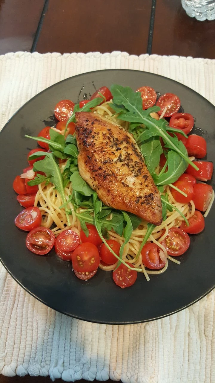 Seared fish fillet over spaghetti with arugula and cherry tomatoes