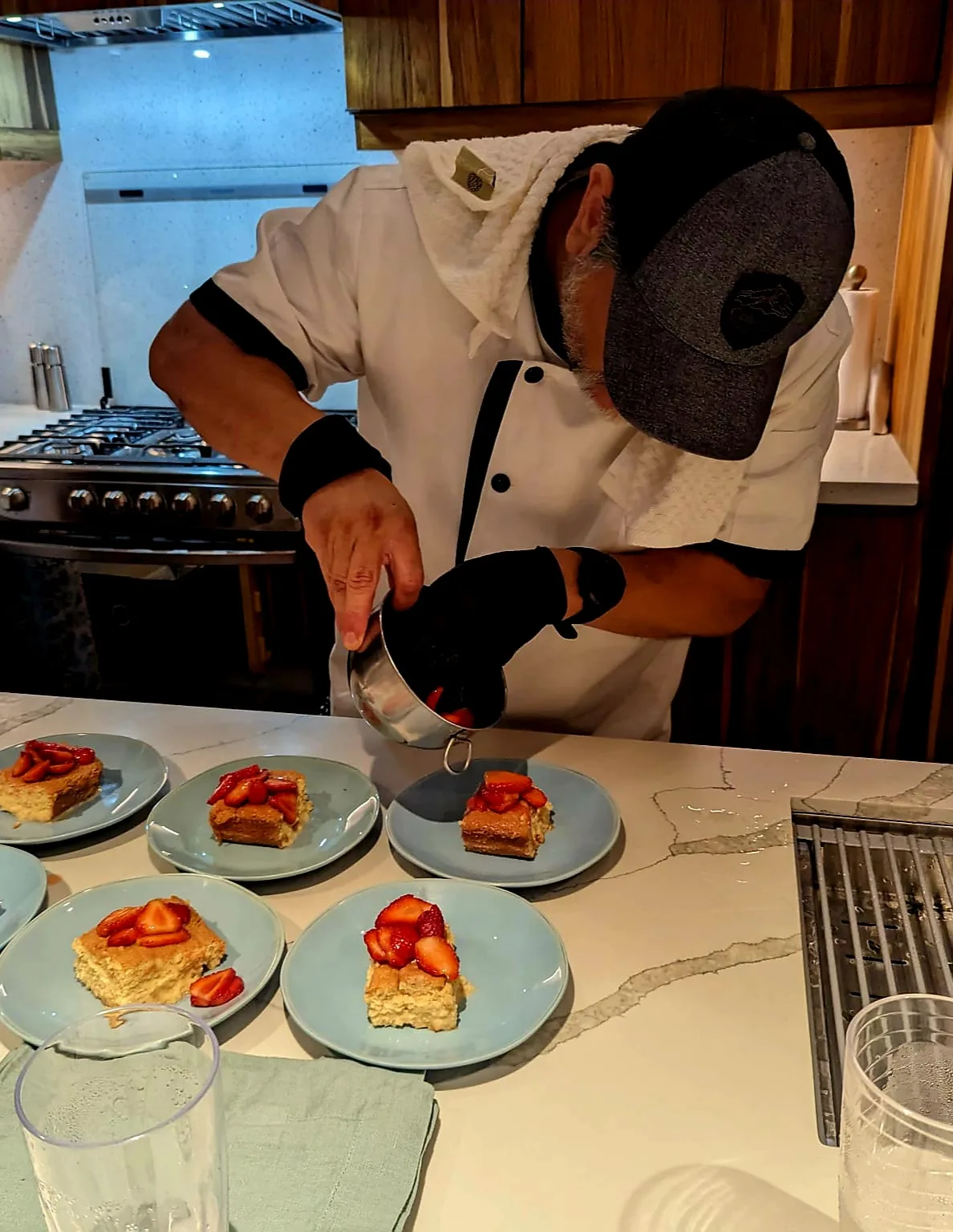 Chef plating cake squares with fresh strawberries for a private dinner