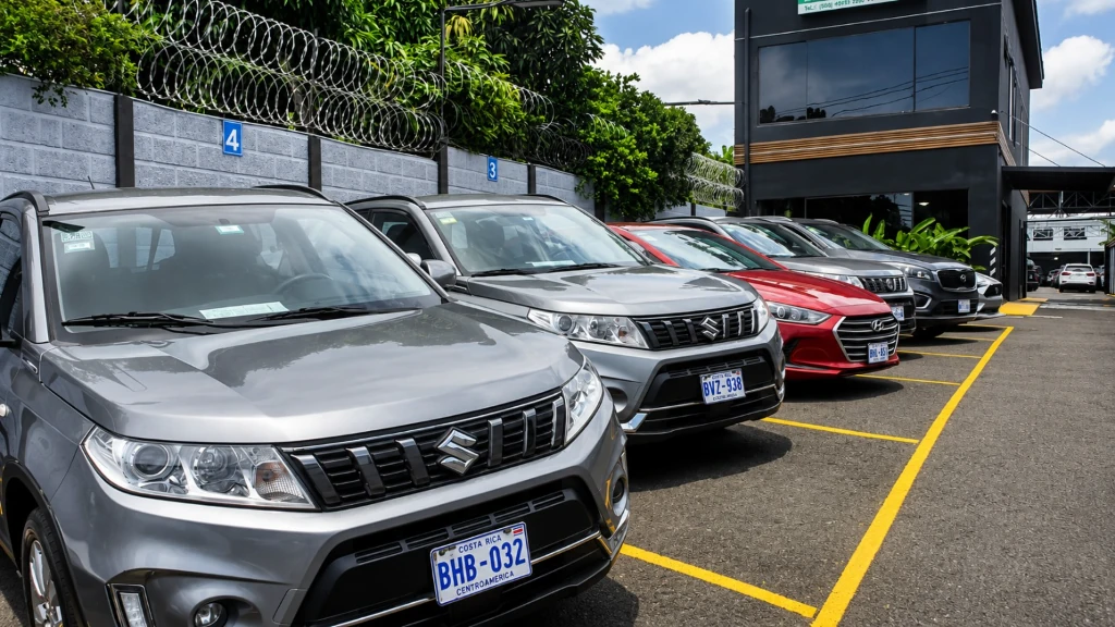 A row of rental SUVs and sedans in marked parking bays