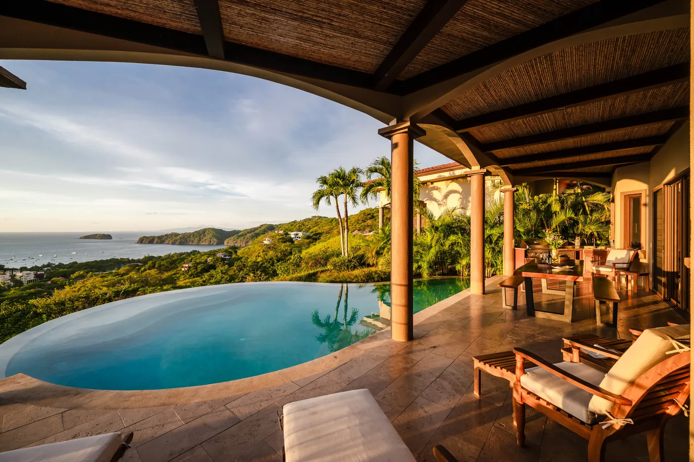 Covered terrace with loungers beside the pool and an open view to the sea
