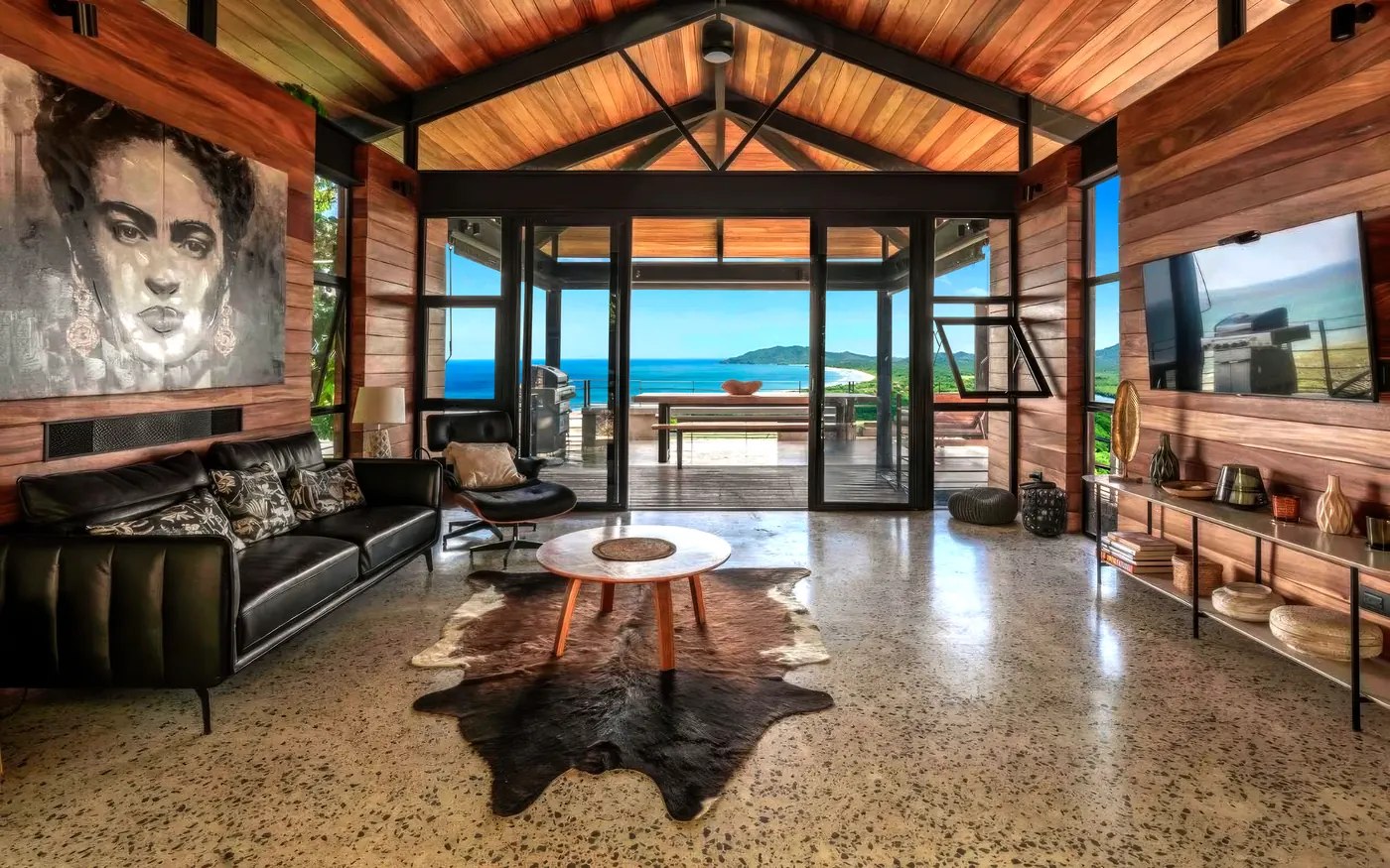 Open living room with a timber ceiling and glass doors onto the ocean-facing terrace